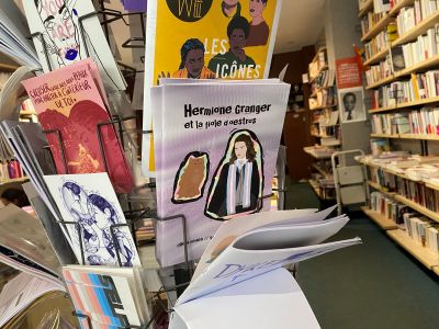 le zine avec la couverture Hermione sur un présentoir avec d'autres zines, cartes postales et revues queers